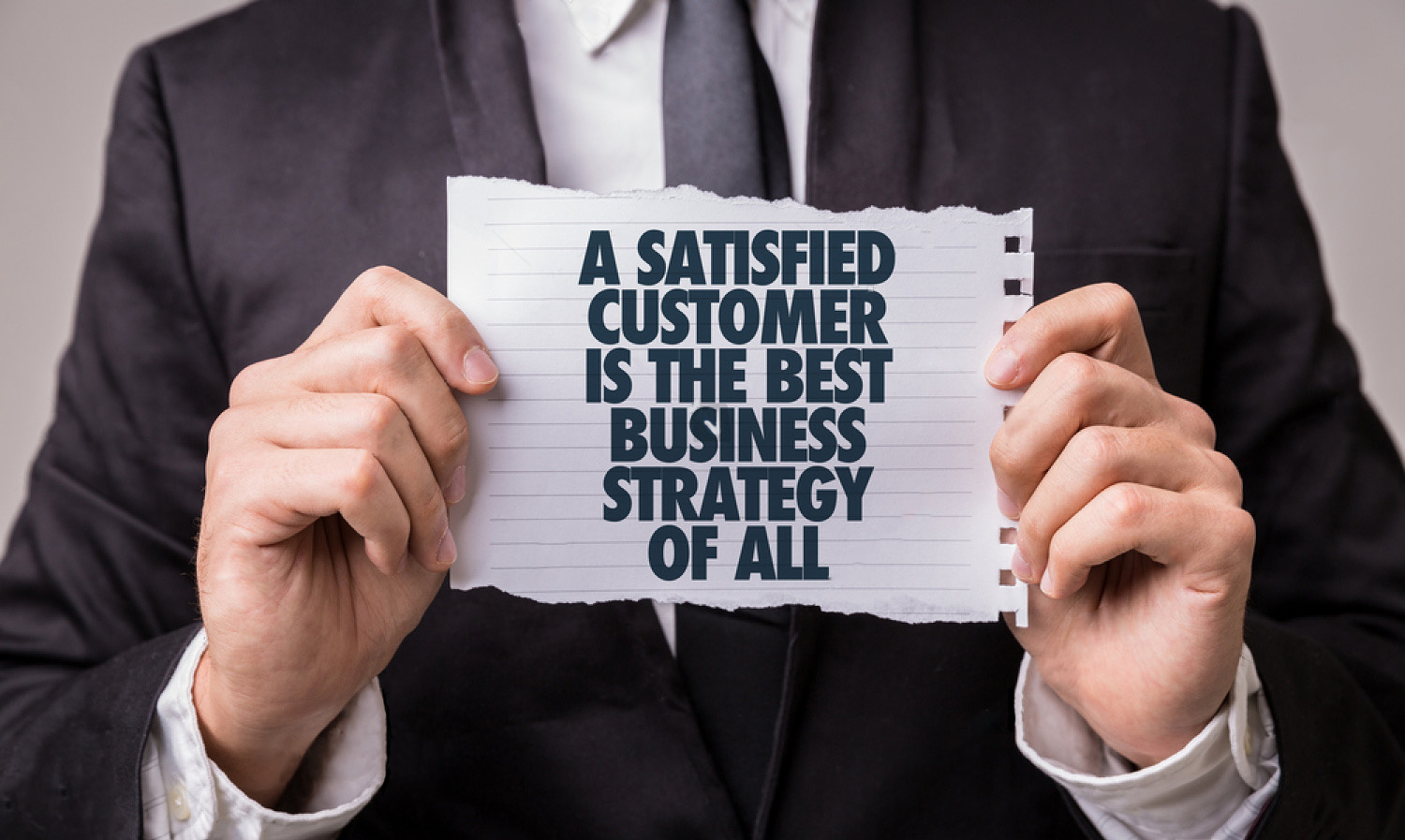 Man holding a sign that says 'A SATISIFIED CUSTOMER IS THE BEST BUSINESS STRATEGY OF ALL'
